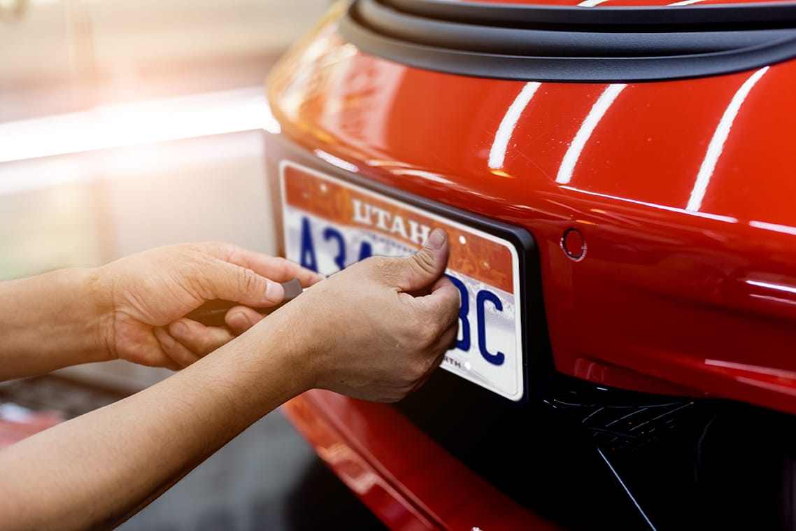 Man pushing thumb on Utah license plate